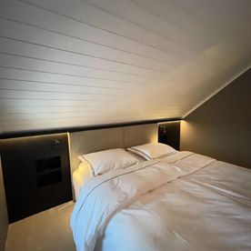 Soverom med skråtak og nattbord med belysning innebygd i vegg